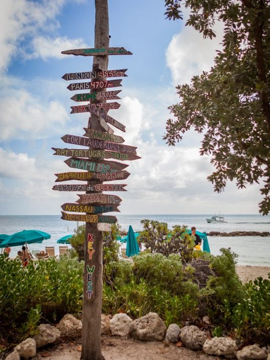 Key West wooden pole with mileage signs to worldwide destinations.