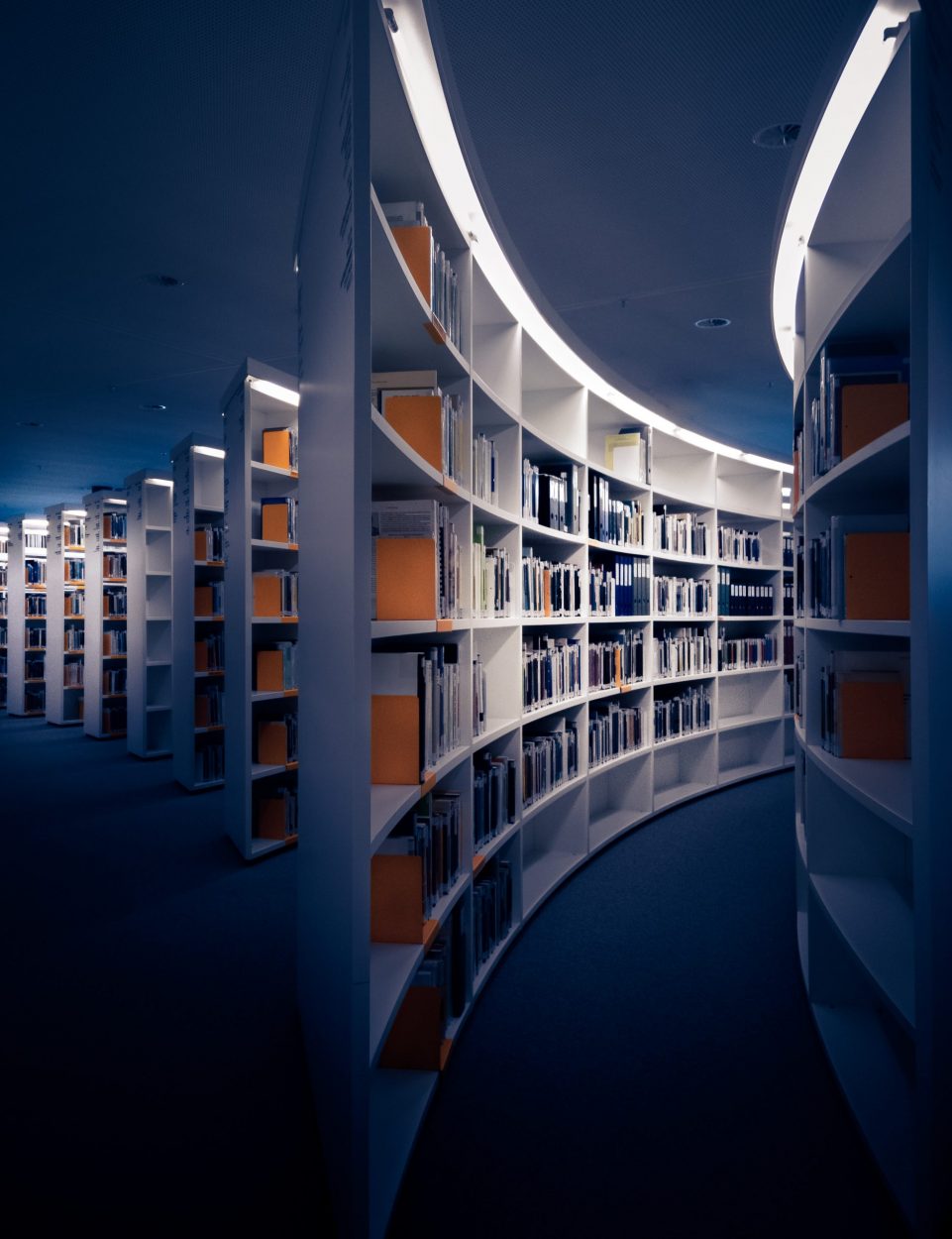 Futuristic curved library shelves filled with books and journals.